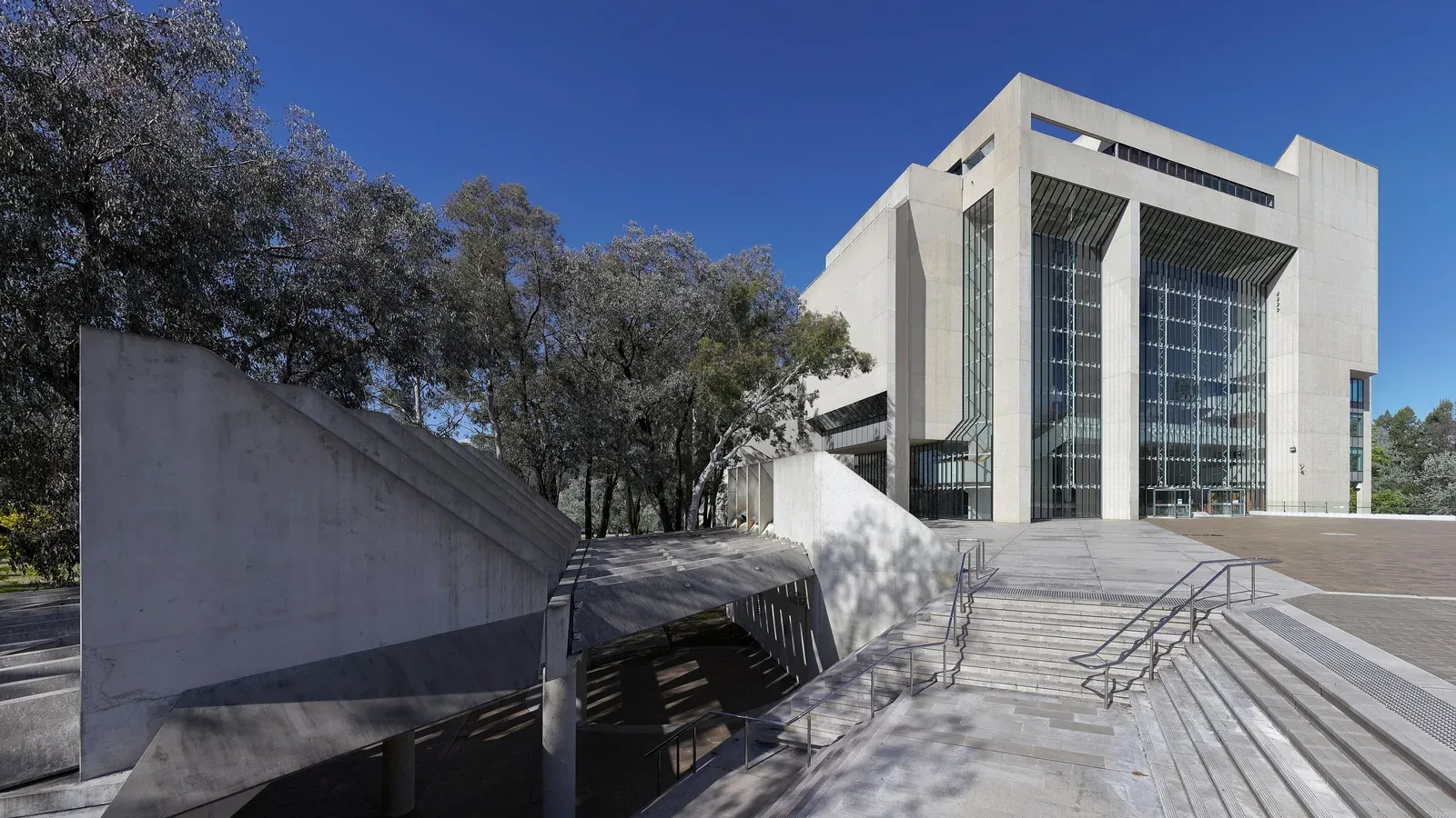 The High Court of Australia in Canberra, a brutalist building with a tall glass atrium, photographed on 10 November 2016. Photo by Thennicke, CC BY-SA 4.0, via Wikimedia Commons.
